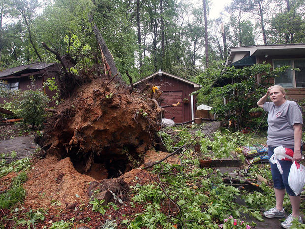 Janette Bentley stands near an uprooted tree in front of her home on Veterans Memorial Parkway after a tornado went through Friday, April 15, 2011, in Tuscaloosa, Ala. 