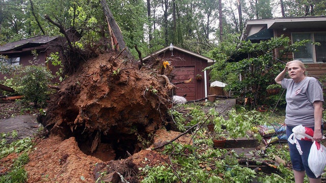 Janette Bentley stands near an uprooted tree in front of her home on Veterans Memorial Parkway after a tornado went through Friday, April 15, 2011, in Tuscaloosa, Ala. 