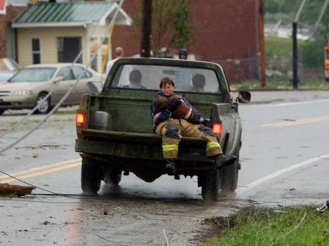 first responder holds onto a child that was found in the rubble of a destroyed home 