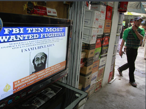 An Afghan youth walks past by a television  announces the death of Al-Qaida leader Osama bin Laden at a television selling market in Kabul, Afghanistan 