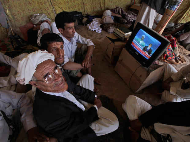Anti-government protestors watch a TV broadcasting a report about the killing of Al-Qaida leader Osama bin Laden 