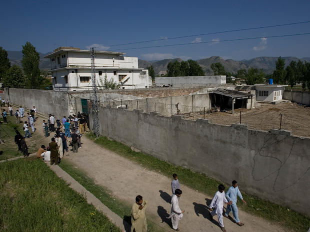 Media and local residents gather outside the house where al Qaeda leader Osama bin Laden was caught and killed, 
