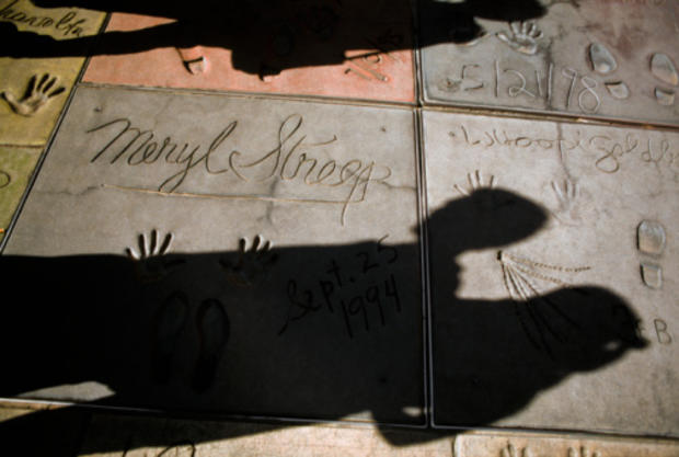 Shadows of tourists look at handprints on Hollywood walk of fame 