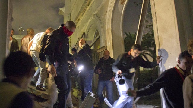 Media and officials tour ruins of building after air strike in Tripoli 