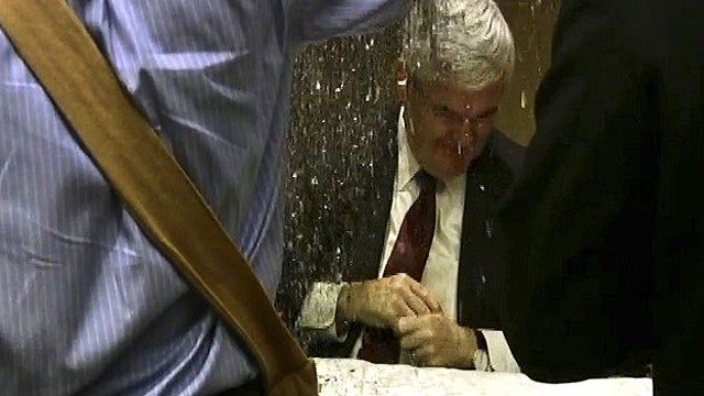 In this image taken from video, a protester dumps glitter on a table where GOP presidential hopeful Newt Gingrich and his wife, Callista, were signing books at a hotel in Minneapolis, May 17, 2011.  