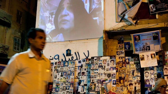 Person walking past screen promoting new TV station 