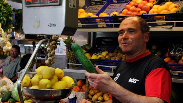Spanish market seller gives vegetable to customer  