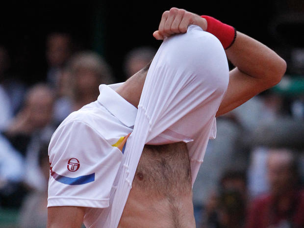 Novak Djokovic covers his face with his shirt 