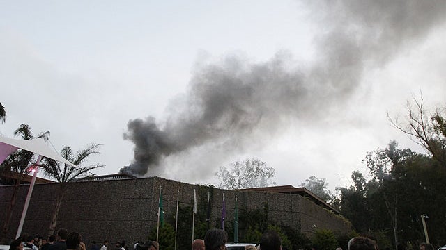 Foreign journalists gather outside of Rixos hotel as plume of smoke rises in the sky in Tripoli, Libya, on June 9, 2011.  