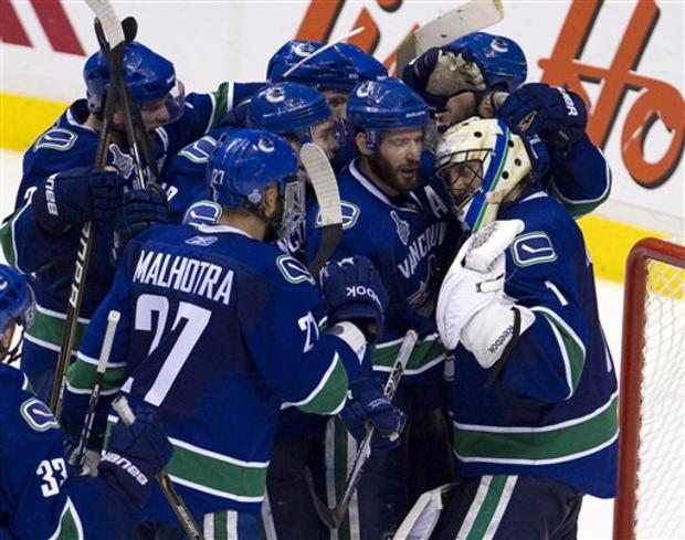 Canucks goalie Roberto Luongo is mobbed by teammates after defeating the Boston Bruins 