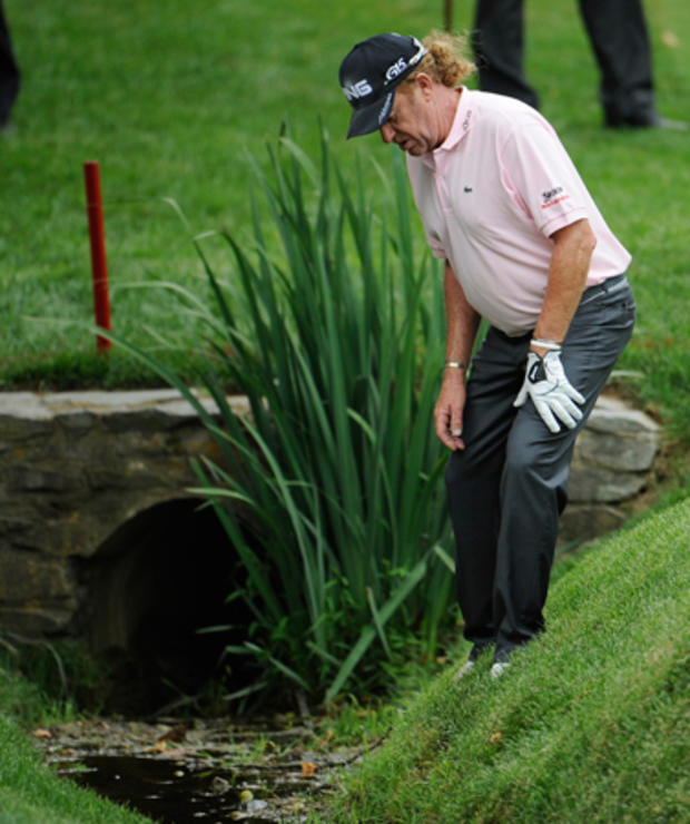 Miguel Angel Jimenez looks for his ball in the water hazard 