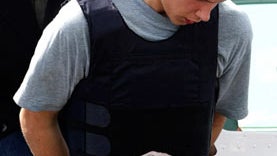 Colton Harris-Moore exits a plane handcuffed as he is escorted by police upon arrival to Nassau, Bahamas, after his arrest before dawn in northern Eleuthera island, on July 11, 2010.  