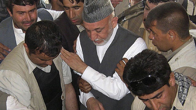 Afghan President Hamid Karzai, center, attends the burial of his half brother Ahmed Wali Karzai in his family's ancestral village of Karz, in Kandahar province, Afghanistan, July 13, 2011.  