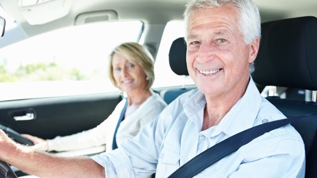 Happy senior couple in car with man on driver's seat 