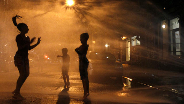 Vanity Mendez, 11, left, Isaiah Rivera, 6, center, and Jonathan Medina, 11, cool off at an open fire hydrant in the East Village neighborhood of Manhattan July 21, 2011. A heat wave that has enveloped much of the central part of the country for the past c 