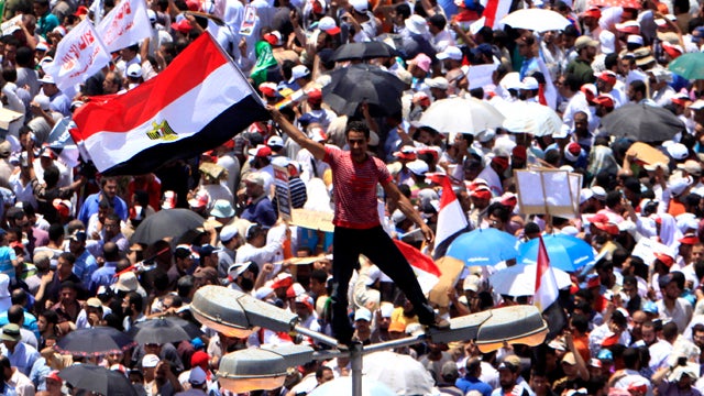 An Egyptian protester waves a national flag as he stands on a light pole at Tahrir Square in Cairo July 29, 2011. Thousands of Egyptians rallied again in the central square seeking to unify their demands despite rifts over key issues between liberal activ 