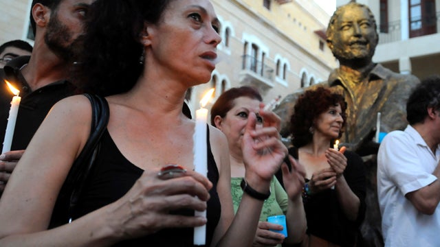 Lebanese activists carry candles during a candlelit vigil in support of the Syrian people in Beirut July 31, 2011, as they stand in front of the statue of late anti-Syrian journalist and activist Samir Kassir, who was killed by a bomb placed under his car 