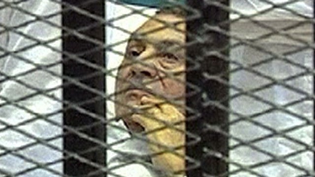 This video image taken from Egyptian State Television shows 83-year-old Hosni Mubarak laying on a hospital bed inside a cage of mesh and iron bars in a Cairo courtroom Aug. 3, 2011 as his historic trial began on charges of corruption and ordering the kill 