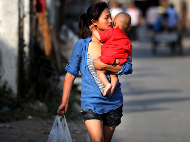 A Chinese woman carries her baby as she makes her way through a slum where they live in Hefei, China, May 21, 2011. 