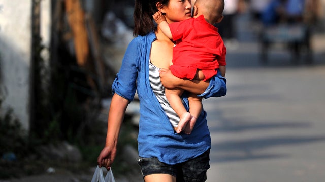 A Chinese woman carries her baby as she makes her way through a slum where they live in Hefei, China, May 21, 2011. 