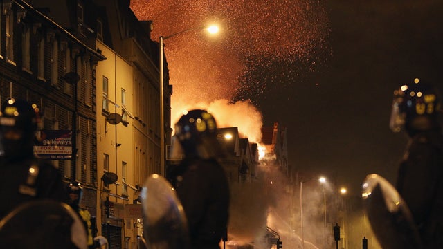 London police watch shops and homes burn in Croydon, south London 