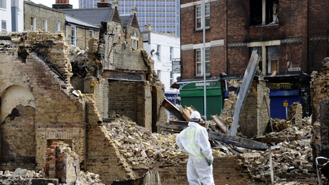 A workman stands guard beside the charred remains of the Reeves furniture shop in Croydon south of London Aug. 10, 2011, following riots in the area the previous night. Prime Minister David Cameron said a "fightback" was underway after four nights of viol 