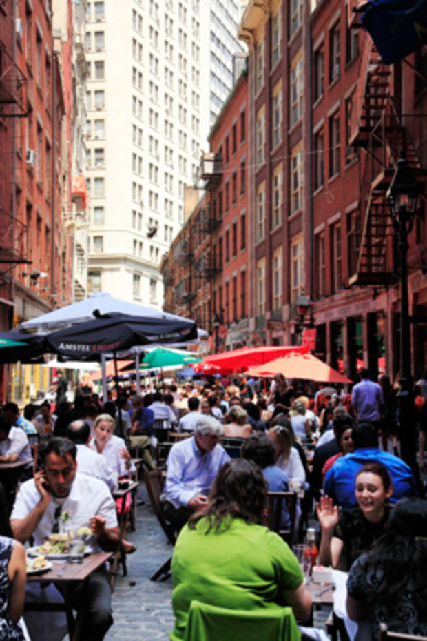 A lunchtime crowd enjoys outdoor table service on Stone Street in New York 