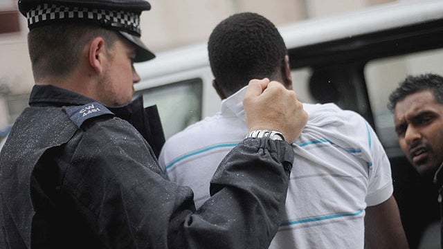 Metropolitan Police officers arrest a suspect, center, after carrying out a raid on a property on the Churchill Gardens estate, in Pimlico, London Thursday Aug. 11, 2011 during an operation to recover property stolen during the recent disturbances in the  