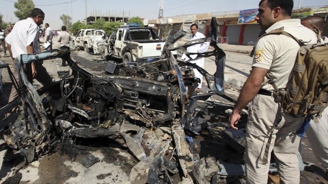Iraqi security forces inspect the site of a suicide bombing in Najaf 