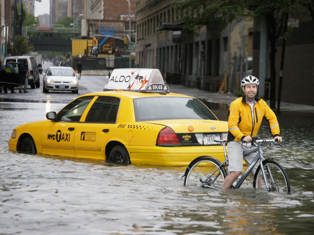 A bicyclist makes his way past a stranded taxi 