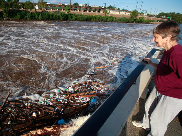 A woman out for a morning walk looks at debris accumulating in the swollen Schuylkill River in Philadelphia, Aug. 29, 201.  