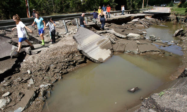 People walk along a washed out section of Route 12 on Aug. 29, 2011, in Berlin, Vt. 