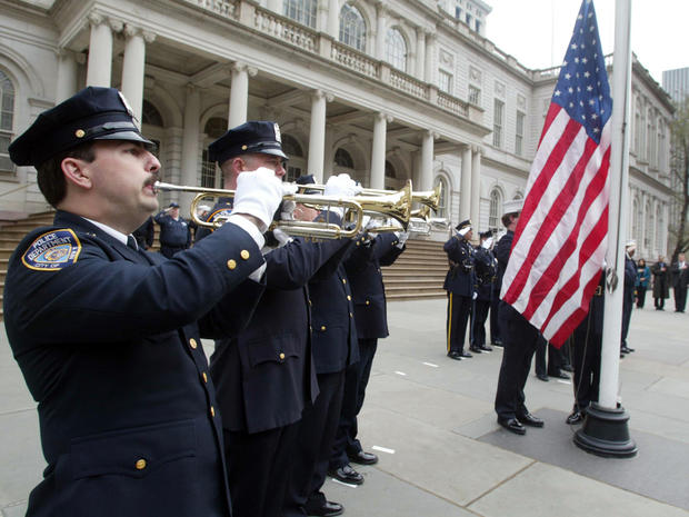 New York Police Department officers play the national anthem as a U.S. flag that once flew over ground zero is raised during a ceremony at City Hall Plaza April 1, 2002, in New York City. The flag was immortalized in a photograph by Thomas E. Franklin of  