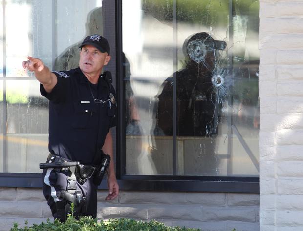 With bullet holes seen in a window, officers look for evidence at the scene of a shooting at an IHOP restaurant in Carson City, Nev. on Sept. 6, 2011. 