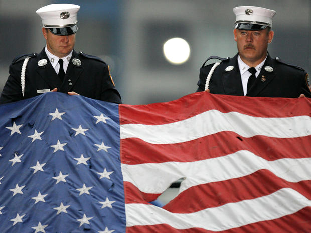 New York City firefighters hold an American flag that was damaged during the 9/11 terrorist attacks during a ceremony at the World Trade Center site Sept. 11, 2007, in New York City. 