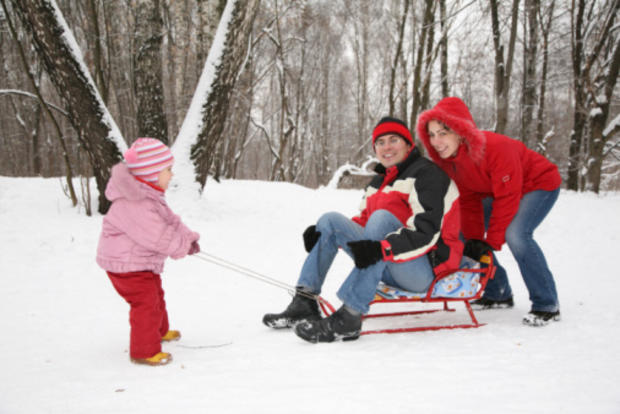 12/23/11 - A Guide To Twin Cities' Sledding Hills –little girl in pink jacket pulling man on sled                                                                                                                 