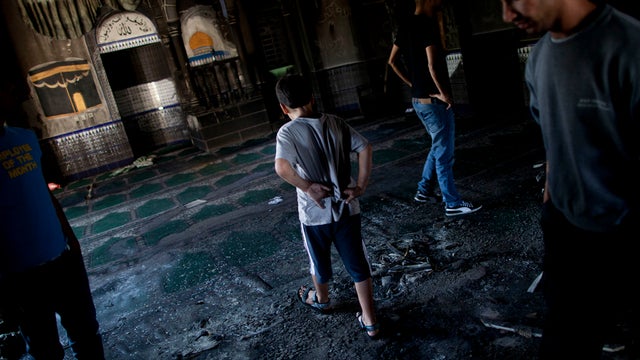 Residents inspect damage caused by an arson attack on a mosque in the Bedouin Arab village of Tuba-Zangria, Israel, Oct, 3. 2011. Arsonists torched the mosque, setting off protests by villagers who later clashed with police. Graffiti sprayed at the site s 