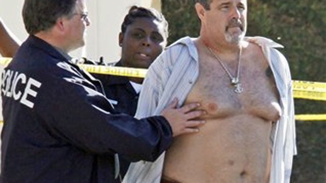 Police officers stand with who was being held in a patrol car at the scene of the arrest of a suspect near the Salon Meritage in Seal Beach, Calif., where a shooting left eight people dead and one critically injured Wednesday, Oct. 12, 2011. Seal Beach po 