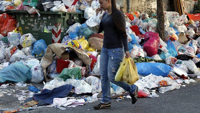 A woman passes by a pile of rotting garbage in Athens Oct. 20, 2011. Garbage collectors have been on strike for more than two weeks. A general strike has paralyzed the country and sent tens of thousands of anti-austerity protesters onto the streets. 