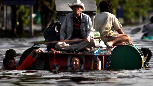 Thai men use makeshift boats to leave a flooded area in Bangkok Oct. 26, 2011. Bangkok residents jammed bus stations and highways to flee the flood-threatened Thai capital while others built cement walls to protect their shops or homes from advancing wate 
