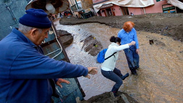 People try to cross a street as water runs through Monterosso, Italy, after overnight floods Oct. 26, 2011. The areas worst hit by the floods in Italy were the Spezia region and the picturesque Five Lands tourist destination, where seven people -- includi 