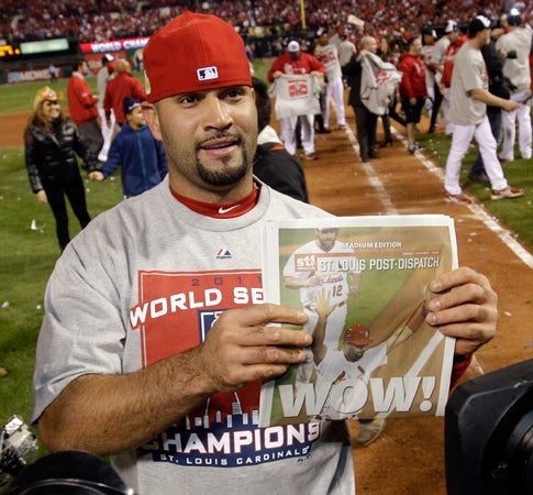 Albert Pujols holds up a newspaper  