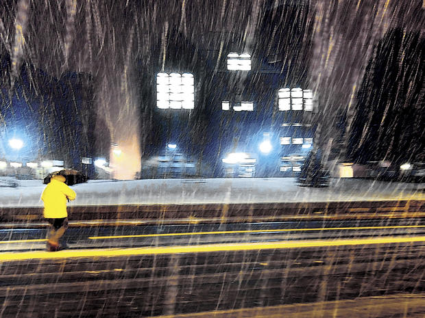 A pedestrian walks in a burst of moderate snow in front of the town hall in Vernon, Conn., during the first snowfall of the season Oct. 27, 2011. More snow is forecast in the Northeast for Oct. 29, 2011. 