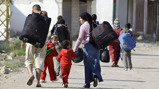 Syrian citizens carry their belongings, as they cross the Lebanon- Syria border illegally to return to Syria, from the village of Arida, north Lebanon, Oct. 31, 2011.  