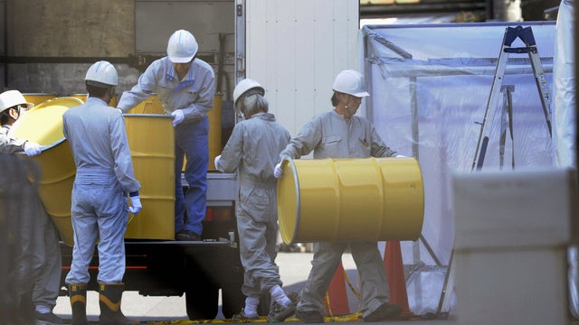 Japanese workers unload metallic drums to discover and remove radioactive material in Tokyo 