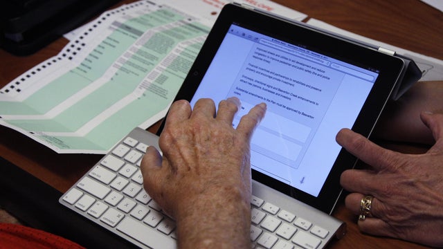 In this Friday, Nov. 4, 2011, photo, Lewis Crew, 75, receives help from a member of a voter assistance team while voting on a iPad, in Beaverton, Ore. Voters in five Oregonian counties are filling out and returning their mail-in ballots for a Tuesday, Nov 