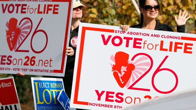 Christi Chandler, left, and Stacy Hawsey, both of Madison and supporters of the Personhood Amendment promote their initiative as they waver signs at drivers in the midst of last minute campaigning Tuesday, Nov. 8, 2011 in Madison, Miss. The Mississippi me 