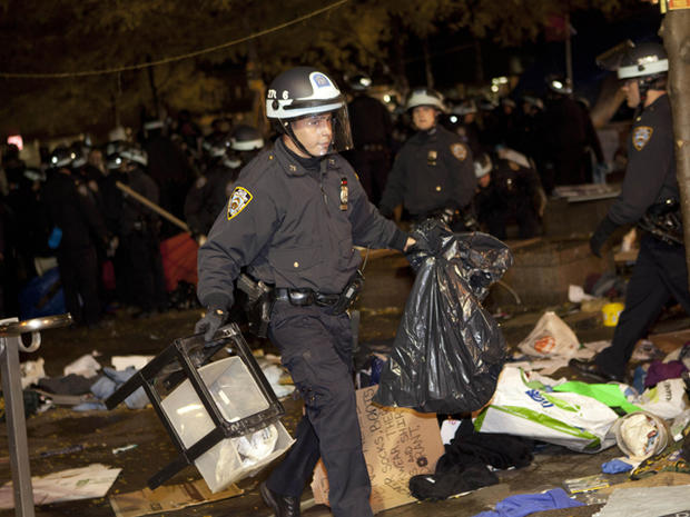A police officer carries trash through Zuccotti Park 