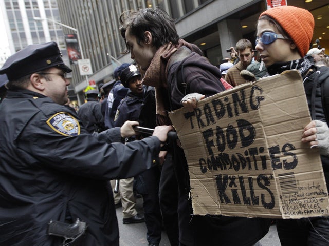A police officer shoves demonstrators affiliated with the Occupy Wall Street movement as they block an entrance to the New York Stock Exchange Nov. 17, 2011, in New York. 