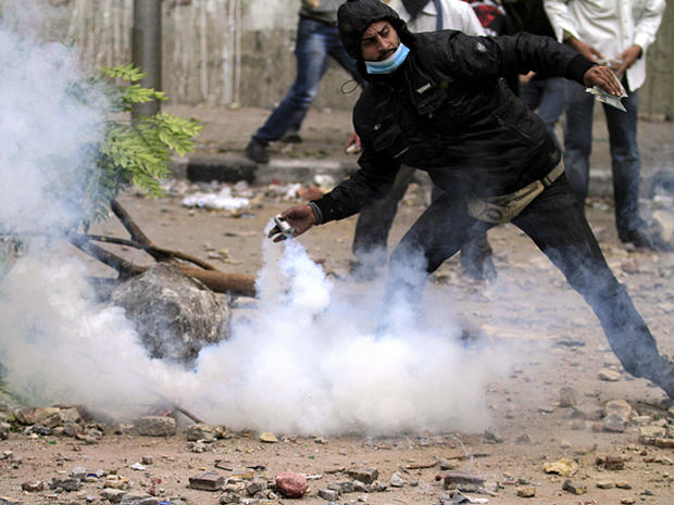 A protester throws  a tear gas grenade back at Egyptian riot police  